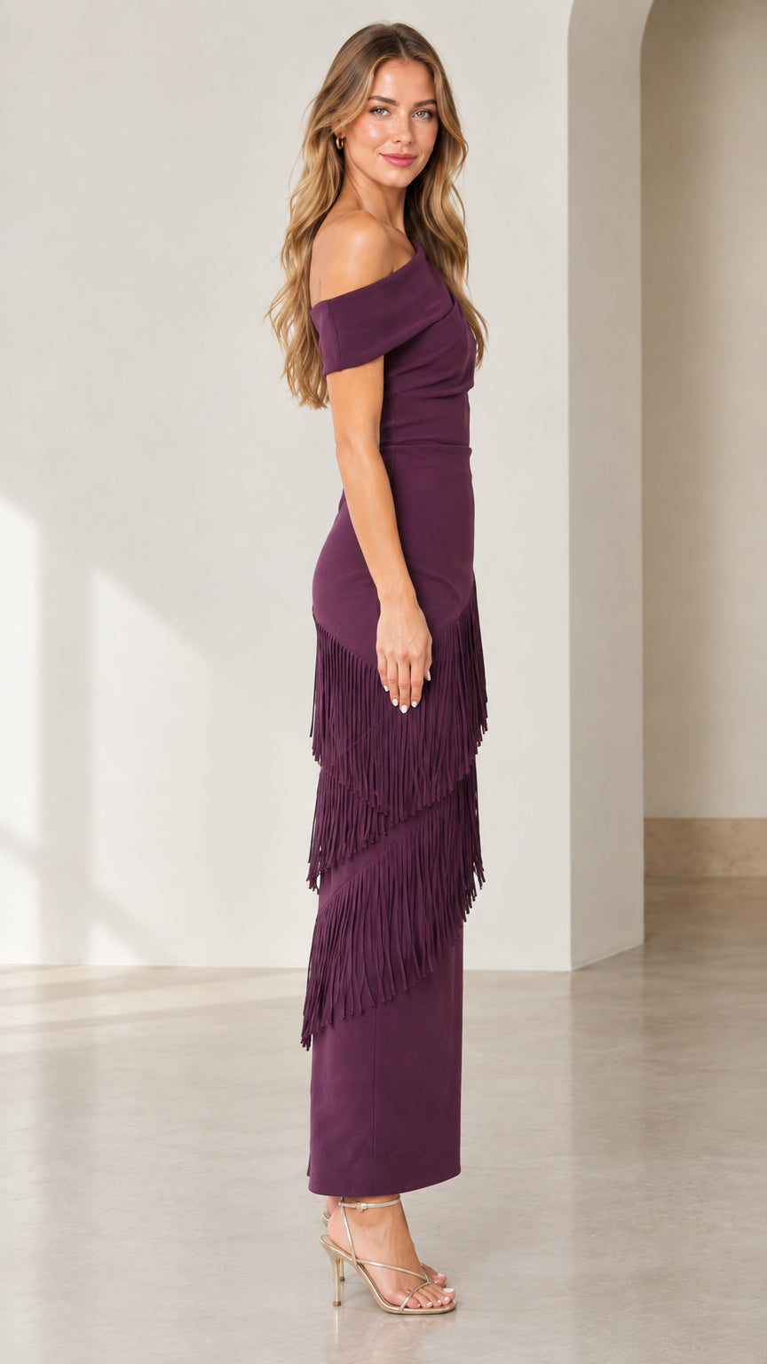 Side full-length view of woman in plum one-shoulder fringe evening dress